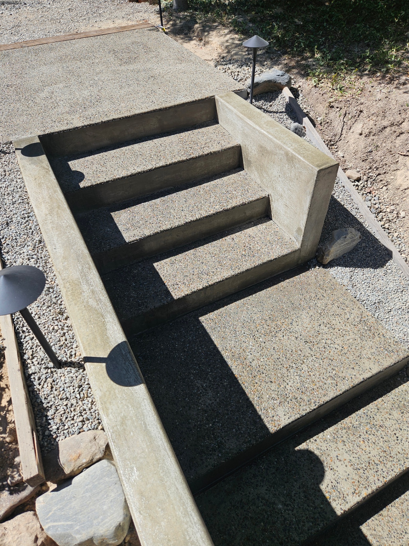 Multi-step exposed-aggregate concrete stairs with integrated landings on a sloped lot